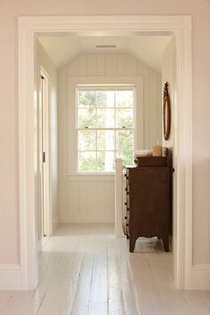 an empty hallway with white walls and wood floors