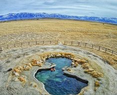 an aerial view of a hot spring in the middle of nowhere with mountains in the background