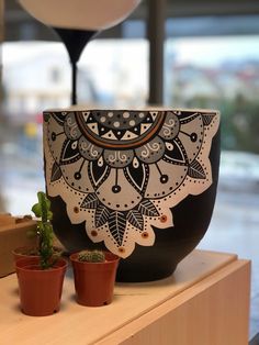 two potted plants are sitting on a shelf in front of a vase with an intricate design