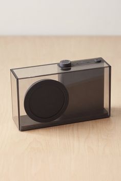 an electronic device sitting on top of a wooden table next to a glass container with a black lid