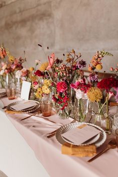 the table is set with flowers and place settings for guests to sit down at it