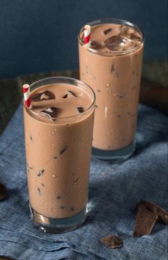 two glasses filled with chocolate milkshakes on top of a blue napkin