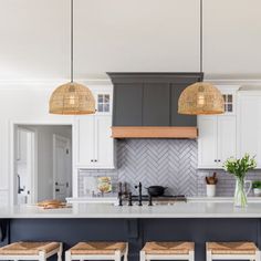 a kitchen with white cabinets and wooden stools in front of an island countertop