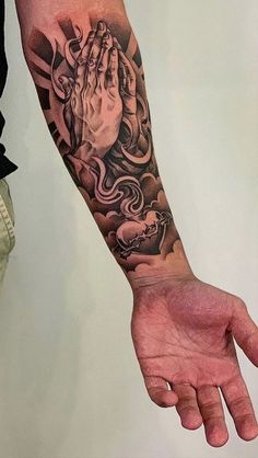 a man's arm with a praying hand tattoo on it