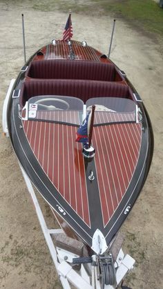 a red and black boat with an american flag on it's side sitting in the sand