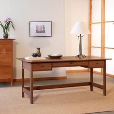 a wooden table with two bowls on it and a lamp next to it in front of a window