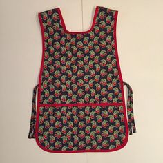 an apron with cherries on it is hanging from the wall next to a pair of scissors