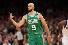 boston basketball player dribbling the ball while standing in front of another player with his hand out