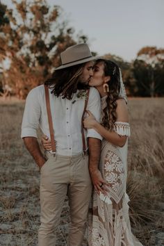 a bride and groom kissing in the middle of a field