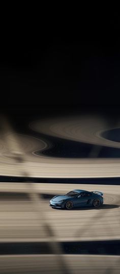 a blue sports car driving on a track in the middle of an empty racetrack at night