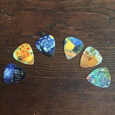 six different colored guitar picks sitting on top of a wooden table