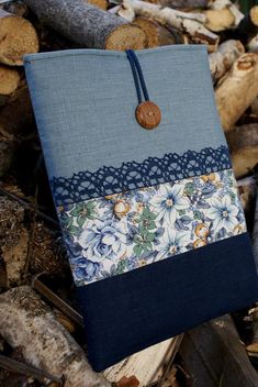 a blue and white flowered bag sitting on top of firewood with a wooden button