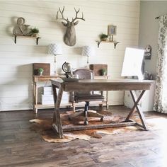 a room with wood floors and white walls, including a wooden desk in the center