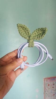 a hand is holding an electronic charger with a leaf on it and plugged in