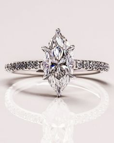 an engagement ring with a pear shaped diamond on the side and pave set shoulders