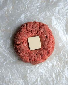 a hamburger with a piece of butter in the middle on top of some wax paper