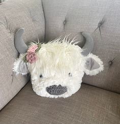 a stuffed animal with horns and flowers on it's head sitting on a couch