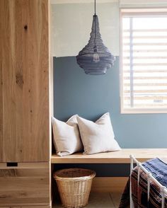 a bedroom with blue walls and white pillows on the bed, next to a wooden bench