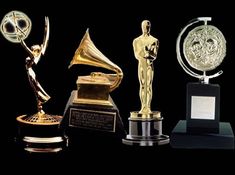 several awards are lined up against a black background, including an award for best musical performance