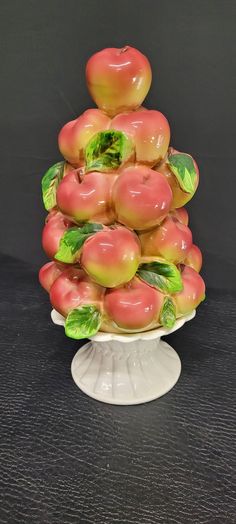 a white plate topped with apples on top of a wooden table next to a black wall