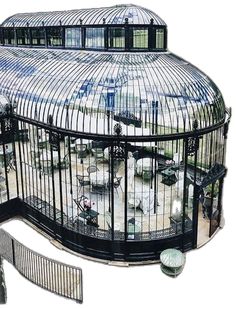 a large glass building with lots of windows on it's sides and an iron fence around the entrance