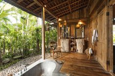 a bathroom with wooden walls and flooring surrounded by greenery