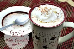 a close up of a cup of hot chocolate with whipped cream in it on a table