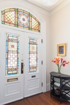 a vase with flowers sitting on top of a table in front of two glass doors