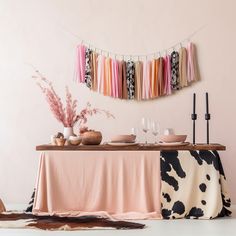 the table is set with plates, glasses and utensils in front of a pink wall