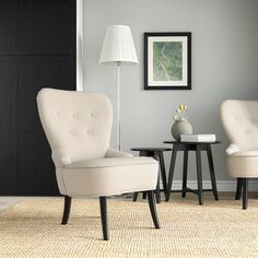 two white chairs sitting next to each other on top of a rug in a living room