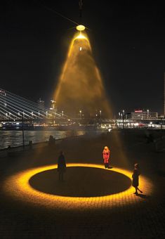 two people standing in the middle of a circular area with lights on it at night