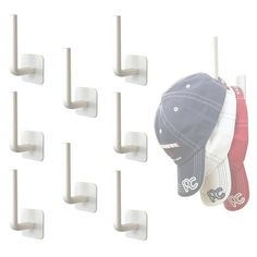 six baseball caps hanging from hooks on a wall