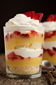 two desserts with strawberries and whipped cream on top are sitting on a table