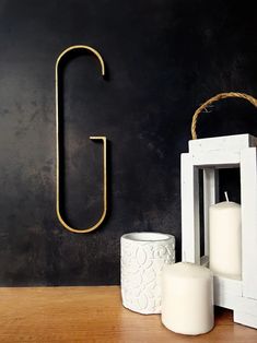 a black wall with some white candles and a wooden letter