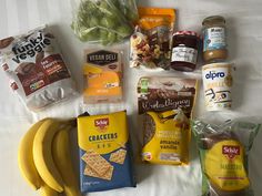 an assortment of food items laid out on a bed with white sheets and striped tablecloth