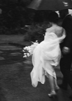 a bride and groom walking under an umbrella