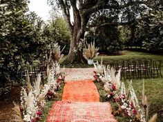 an outdoor wedding ceremony setup with flowers and rugs on the ground, surrounded by trees