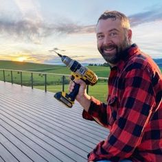 a man sitting on a deck holding a drill