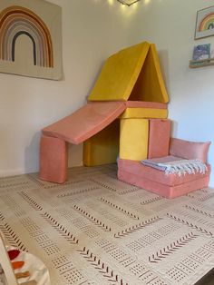 a child's play room with pink and yellow furniture in the shape of a house