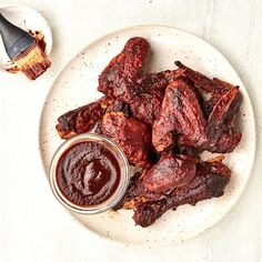 a white plate topped with meat next to a jar of bbq sauce