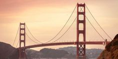 the golden gate bridge in san francisco, california is seen at sunset as boats pass under it