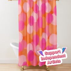 an orange and pink shower curtain with white polka dots on it in front of a bathtub