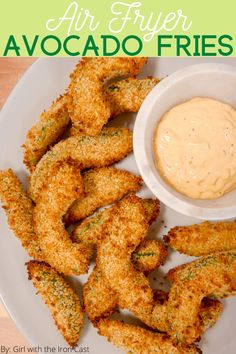 air fryer avocado fries on a white plate with dipping sauce in the middle