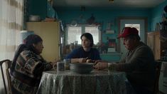 three people sitting at a table in a kitchen