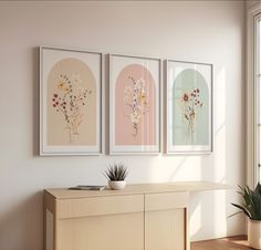 three framed paintings on the wall above a dresser