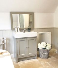 a bathroom with a sink, mirror and basket of flowers on the floor next to it