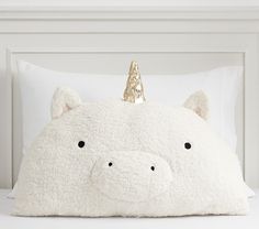 a white pillow with a gold animal head on it's side, sitting on top of a bed