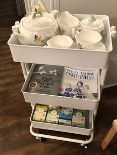 a cart filled with tea cups and saucers sitting on top of a wooden floor