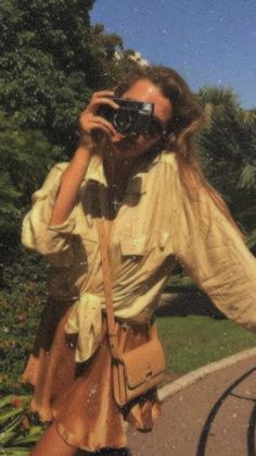 a woman taking a selfie with her camera in front of some flowers and trees