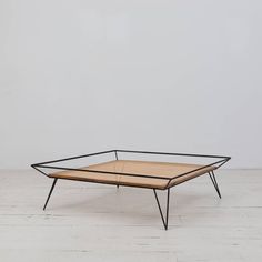 a wooden table with black metal legs on a white floor